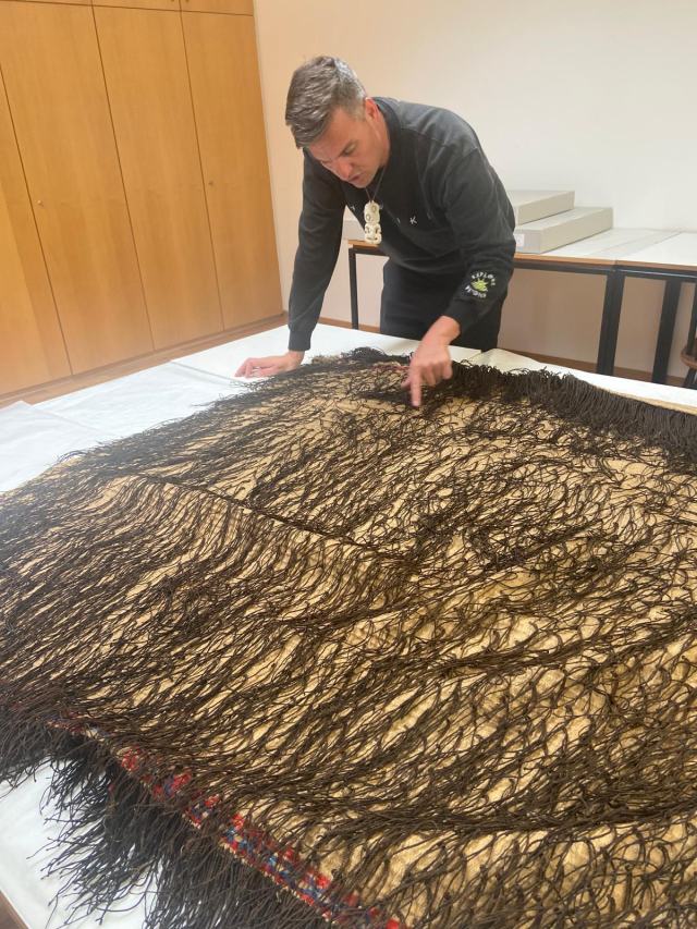 Examining a kākahu held in a museum collection